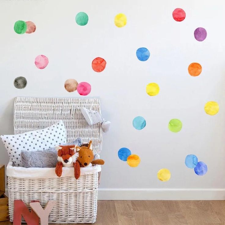 a child's room with polka dot decals on the wall and a basket full of toys