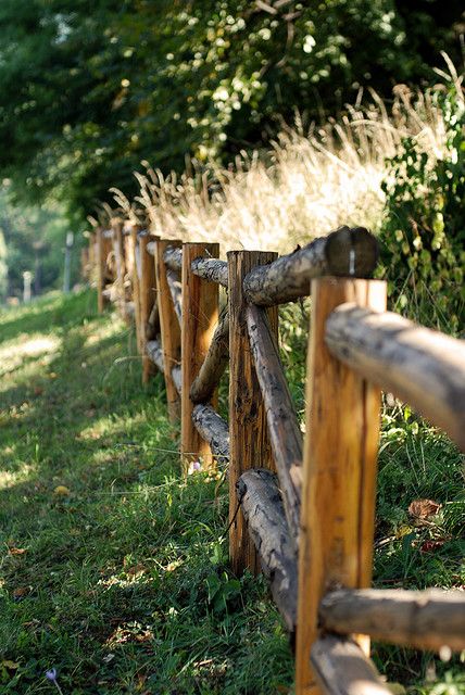 a wooden fence in the grass next to trees