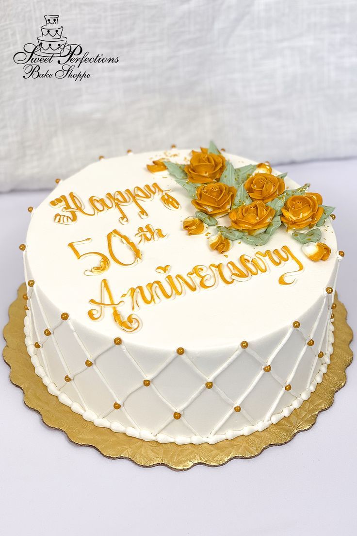 a white and gold 50th anniversary cake with roses on the top is decorated in gold