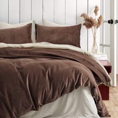 a bed with brown sheets and pillows in a bedroom