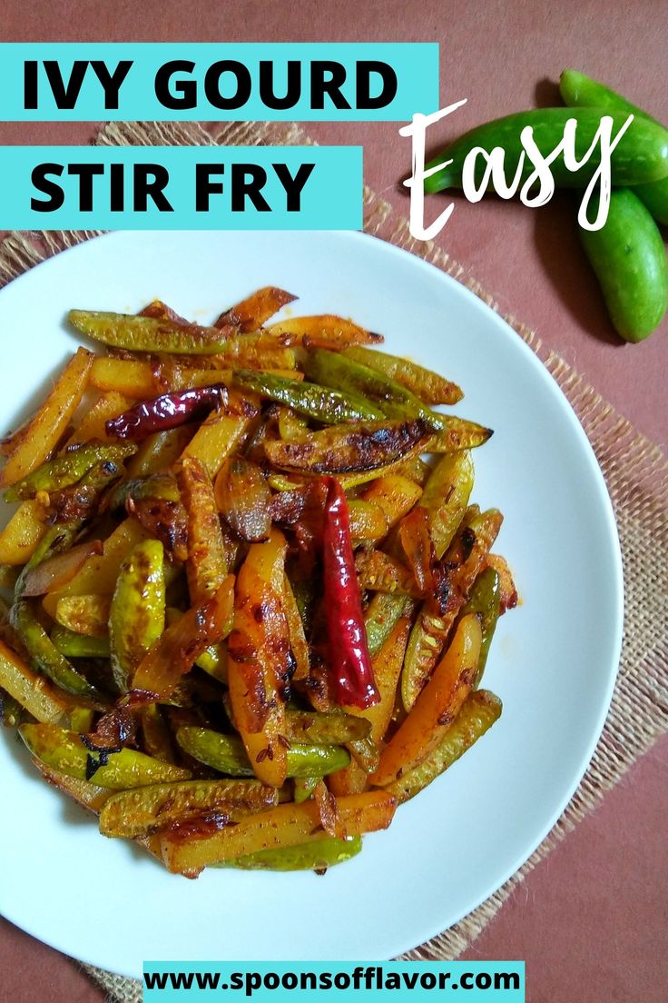 a white plate topped with fried vegetables on top of a table next to a green pepper