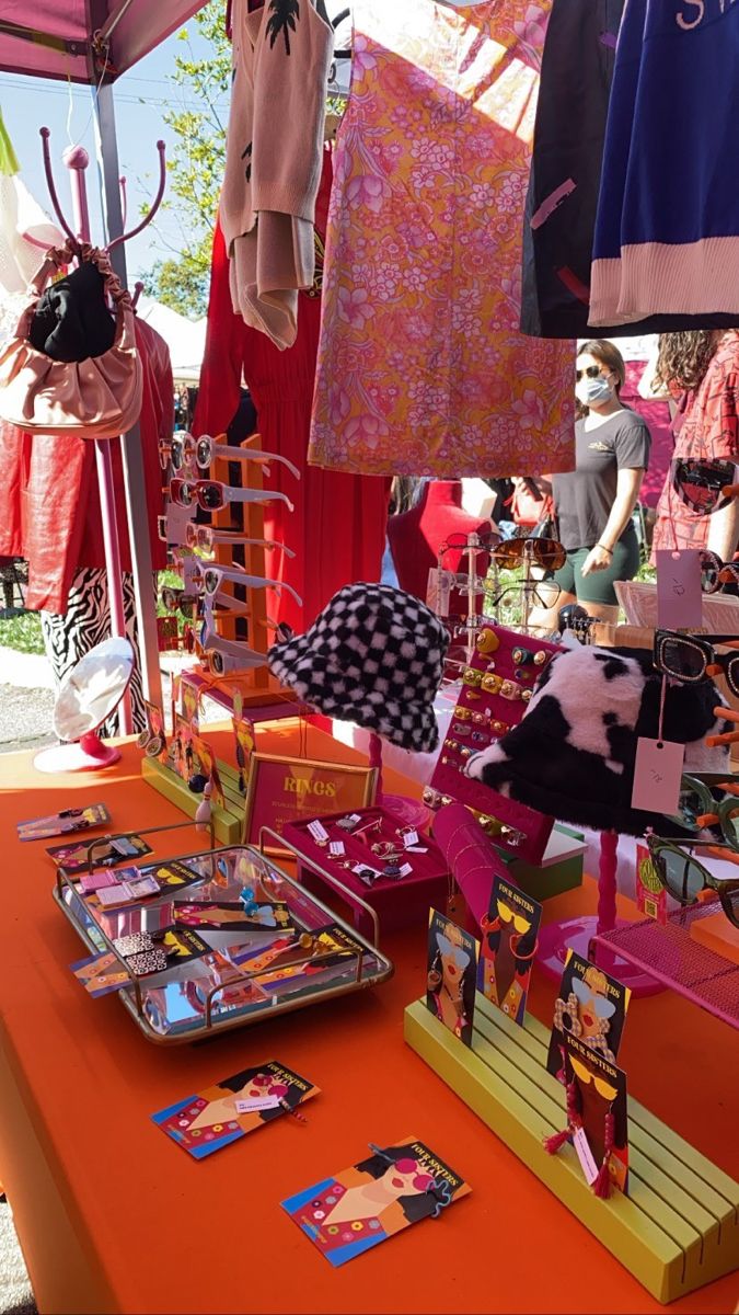 an orange table topped with lots of clothing and items on display in front of people