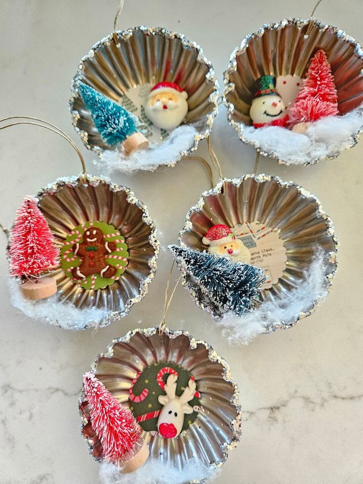 four tin can christmas ornaments in the shape of seashells on a marble surface