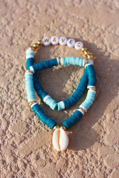 two bracelets with shells and beads on sand