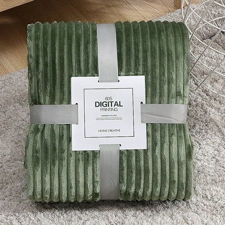 a green blanket sitting on top of a white rug