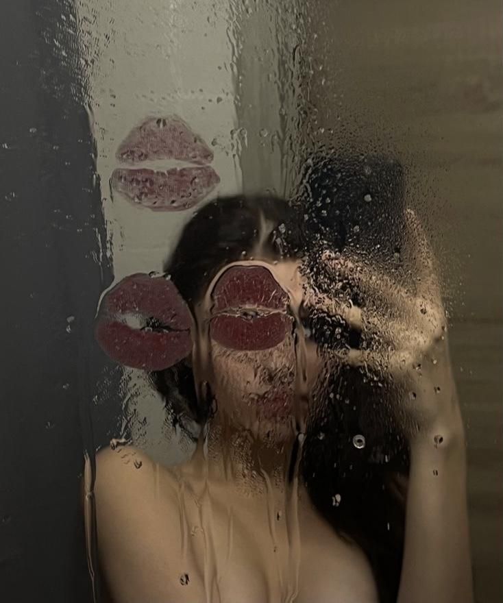 a woman standing in front of a shower with her hands on her head and two red lips sticking out of the window