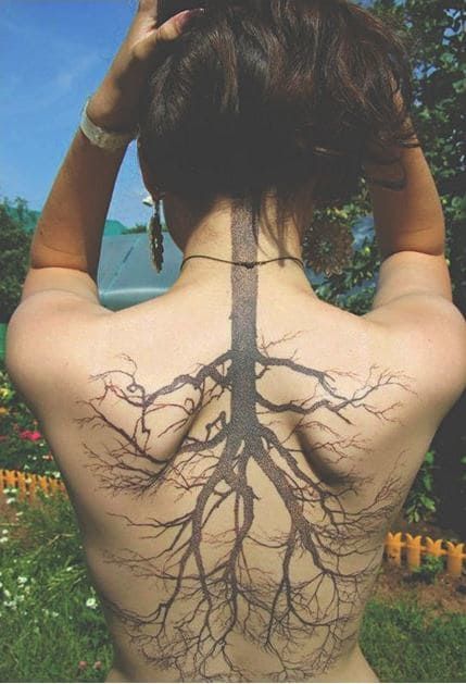 the back of a woman's body with tree roots on her upper and lower back