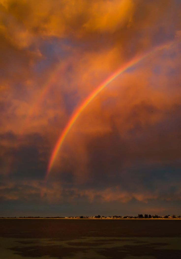 a rainbow in the sky with clouds above it