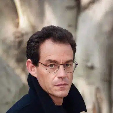 a man wearing glasses and a black coat