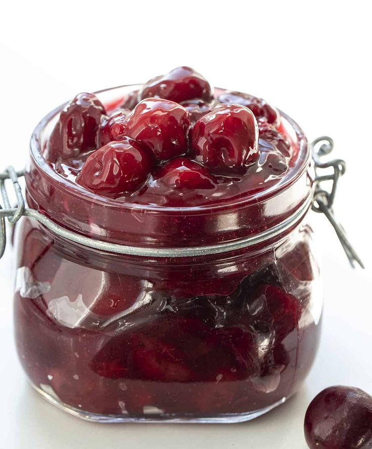 a jar filled with cherries sitting on top of a table