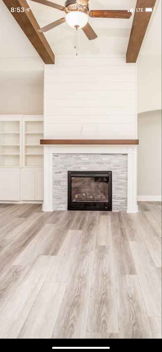 an empty living room with a fireplace and ceiling fan