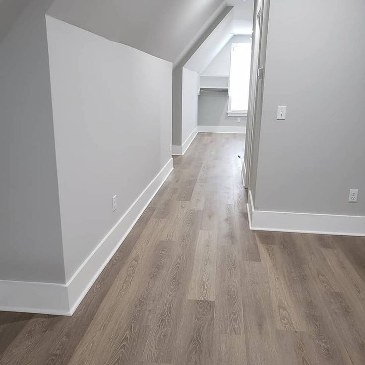 an empty room with white walls and wood floors