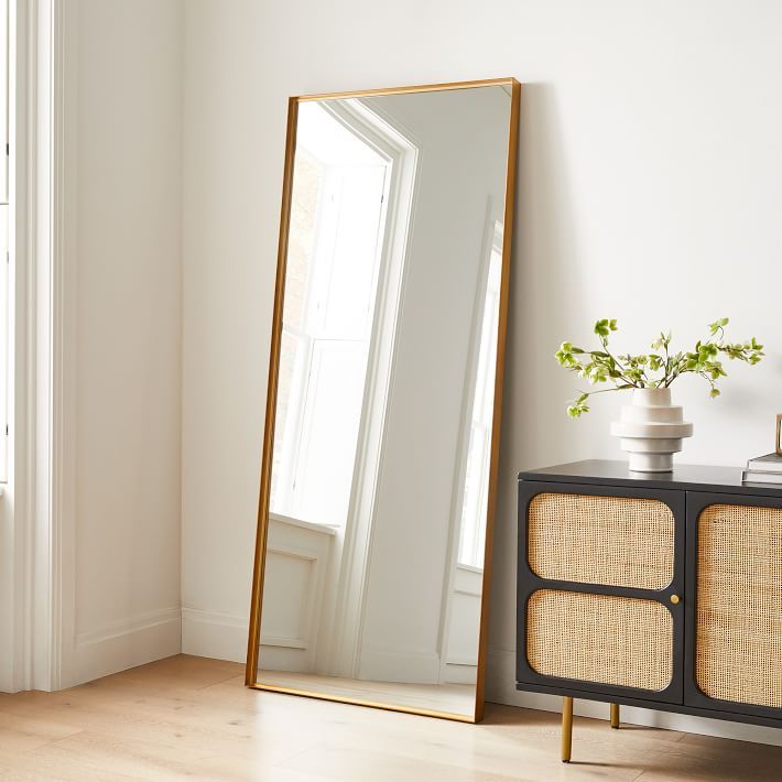 a mirror sitting on top of a dresser next to a vase with flowers in it