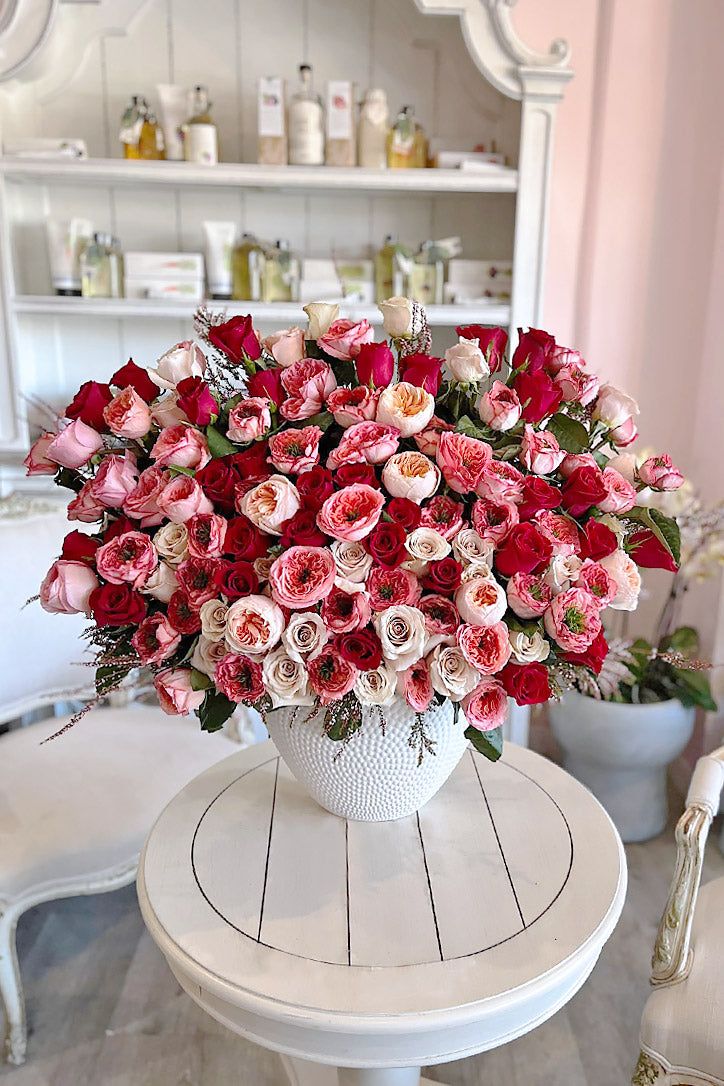 a white table topped with a vase filled with red and pink flowers on top of it