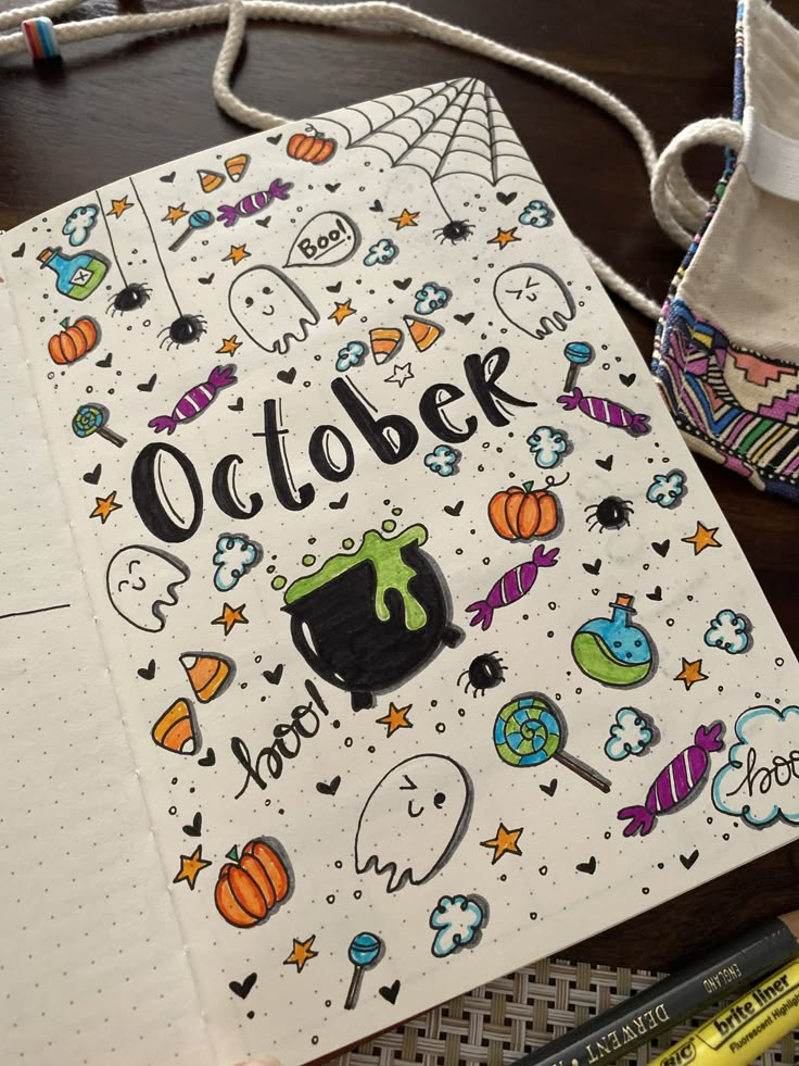 an open notebook with the words october written on it next to crayons and markers