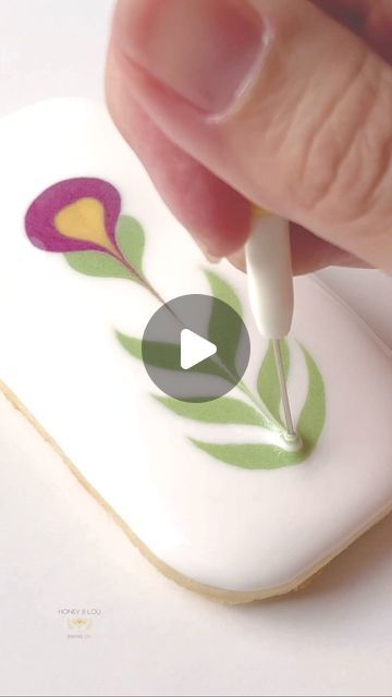 a person is using a pen to draw flowers on a cookie