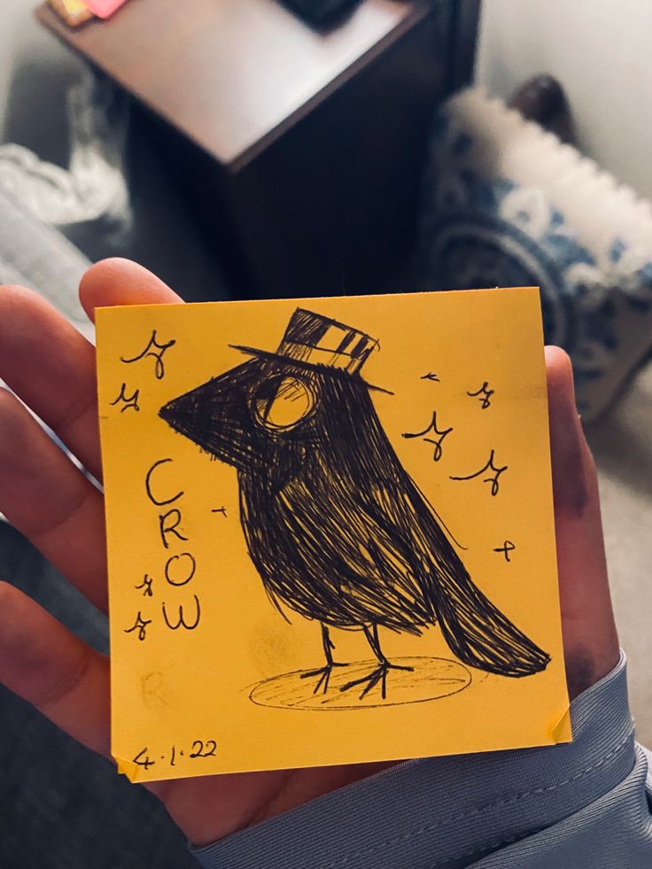 a person holding up a yellow piece of paper with a drawing of a bird on it