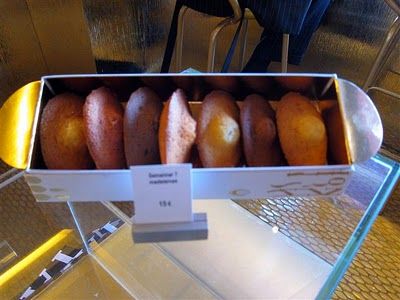 a box filled with donuts sitting on top of a glass counter next to chairs