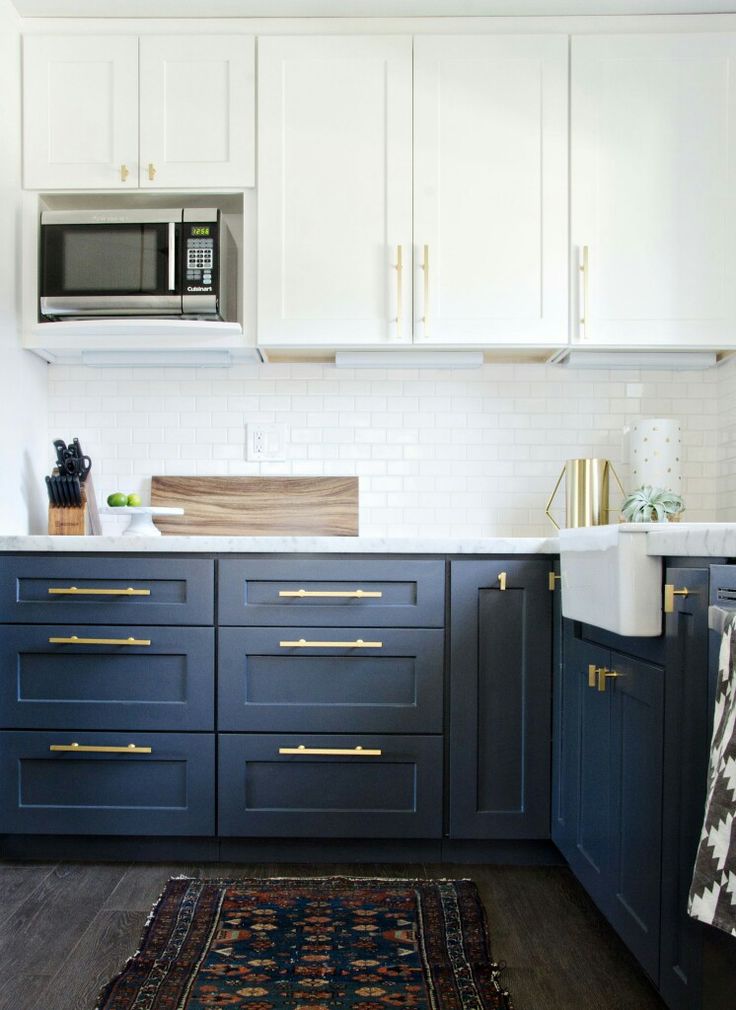 a kitchen with blue cabinets and gold pulls on the handles, along with a rug