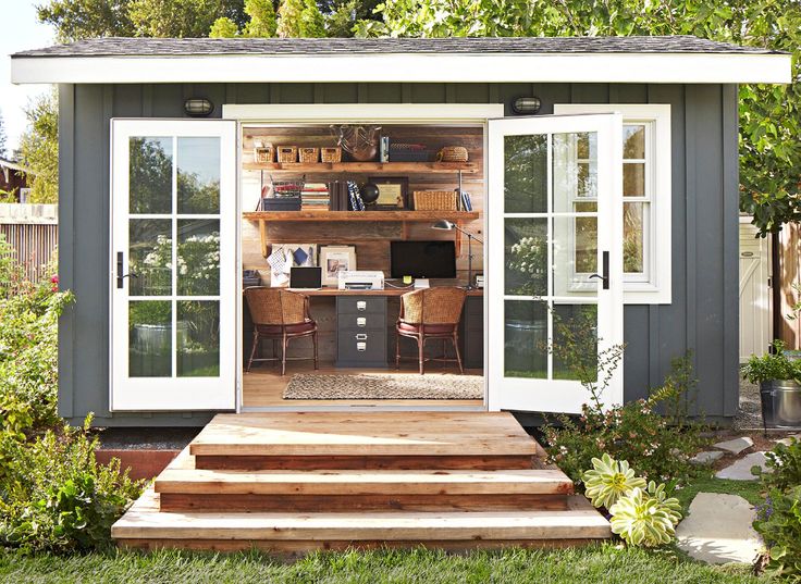 an outdoor office is built into the side of a shed with sliding glass doors on it