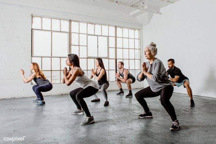 a group of people in a dance class doing squats and standing on one leg