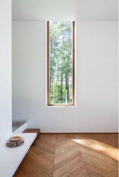 an empty room with wooden floors and a window in the corner that looks out onto the woods