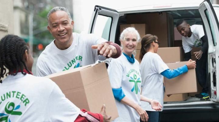 several people in white shirts loading boxes into a van