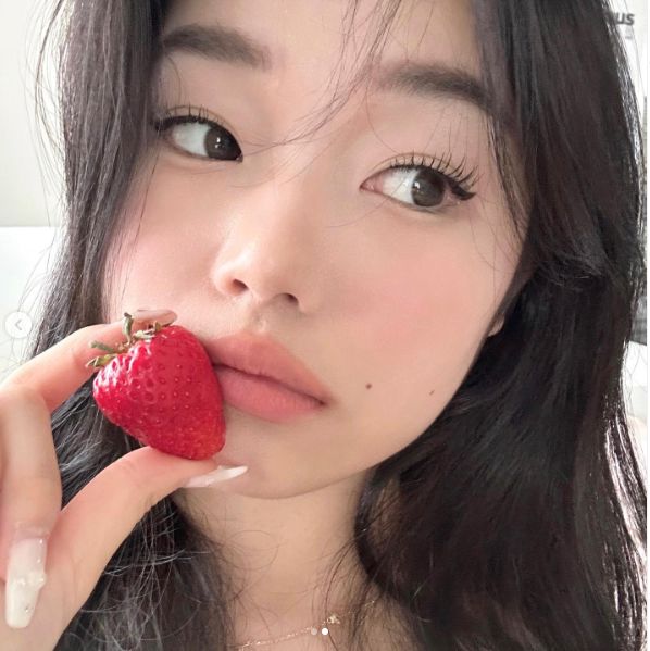 a woman holding a strawberry in her mouth