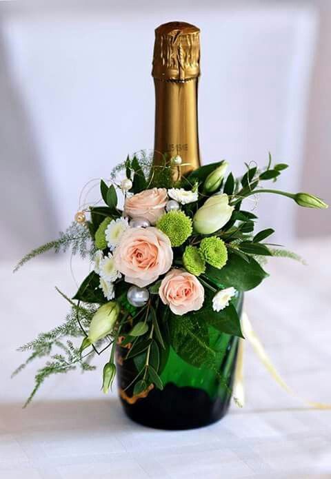 a champagne bottle filled with flowers and greenery