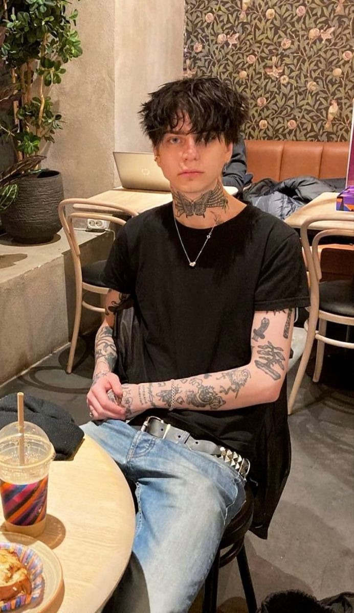 a man with tattoos sitting at a table