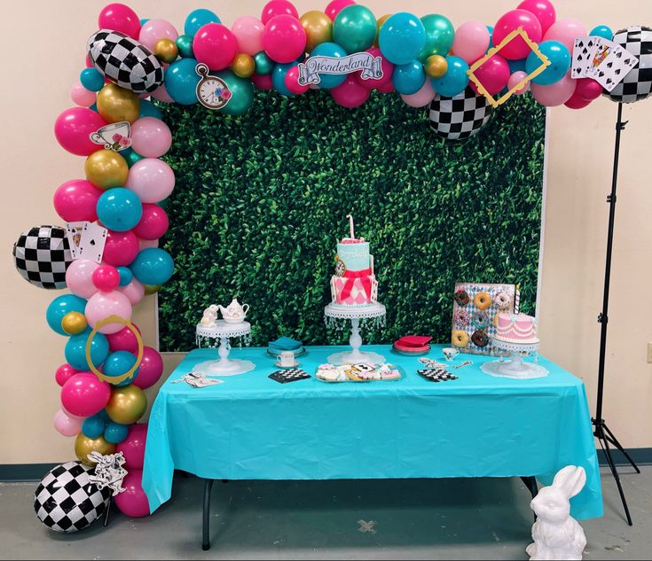 a blue table topped with cake and balloons