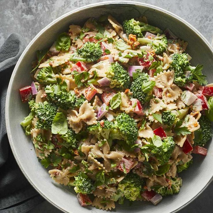 a bowl filled with pasta and broccoli on top of a gray countertop