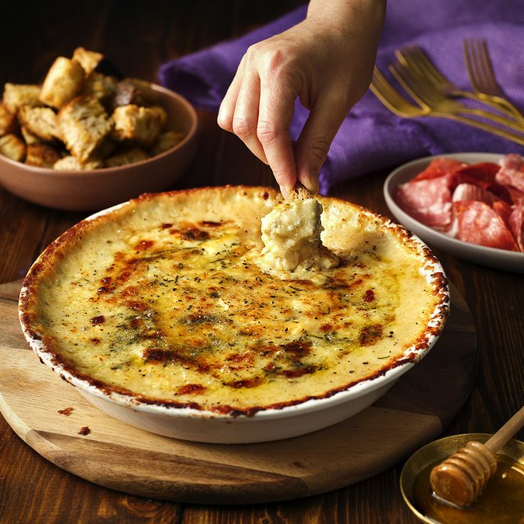 a person dipping some food into a dish on a wooden table next to other dishes