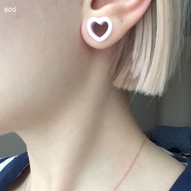 a close up of a person wearing earrings with a heart on the back of their ear