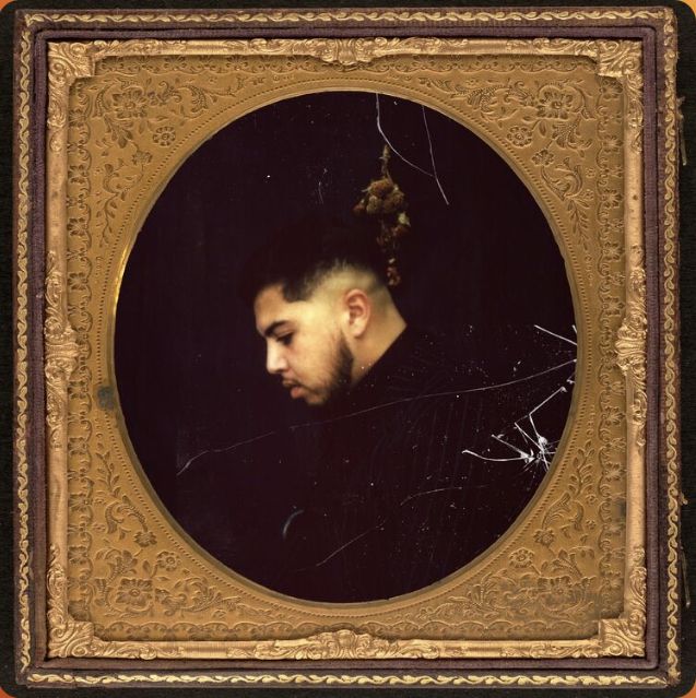 a portrait of a man with a bun in his hair is framed by an ornate gold frame