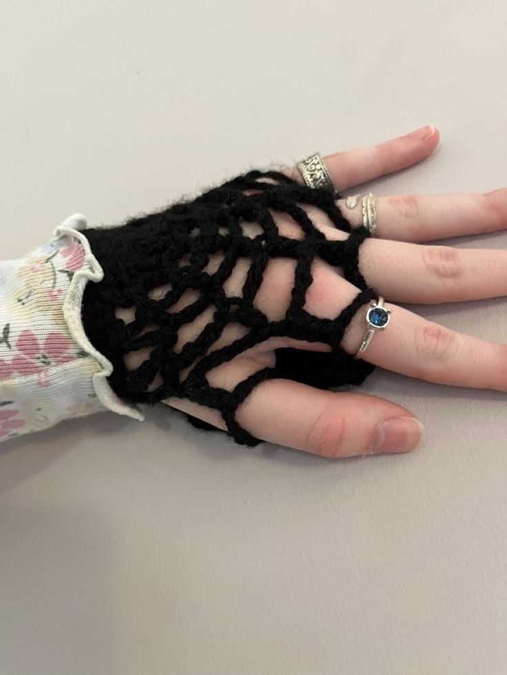 a woman's hand wearing a black crochet knitted ring and bracelet