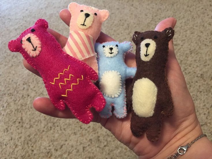 four small stuffed animals are held in someone's hand