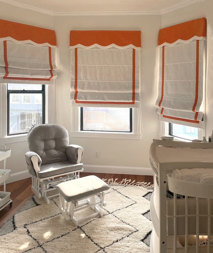 a baby's room with white furniture and orange drapes on the windowsills