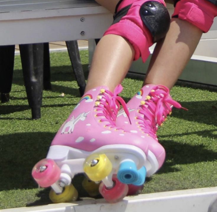 a person wearing pink roller skates and knee pads sitting on top of a bench