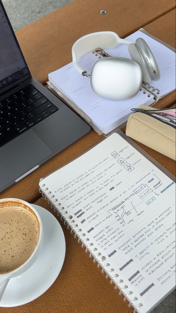 a laptop computer sitting on top of a wooden desk next to a cup of coffee