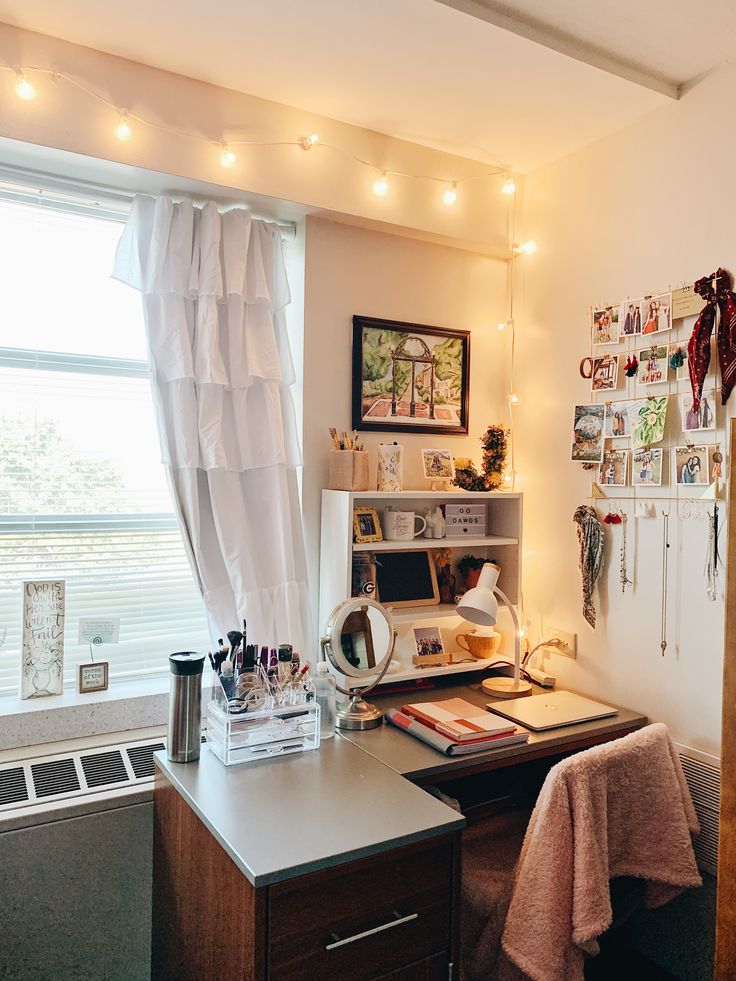 a room with a desk, shelves and pictures on the wall above it in front of a window