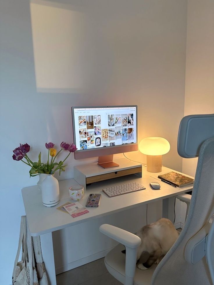 a white desk with a computer monitor, keyboard and mouse next to a flower pot