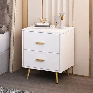 a white night stand with two gold handles on it next to a bed and nightstand