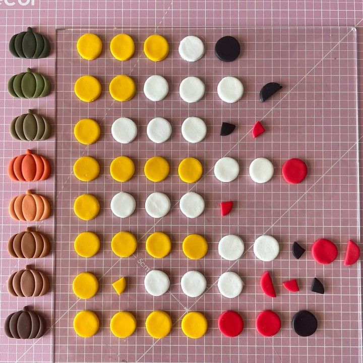 several different shapes and sizes of buttons on a cutting board with a pink grid in the background