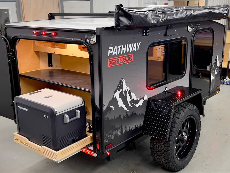 an off road camper trailer with the back door open and its storage compartment opened