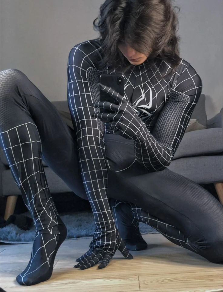 a woman in black and white checkered tights looking at her cell phone while sitting on a couch