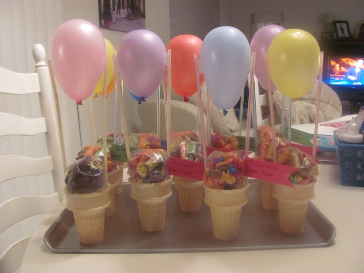 ice cream cones with candy and balloons in them on a tray at a birthday party