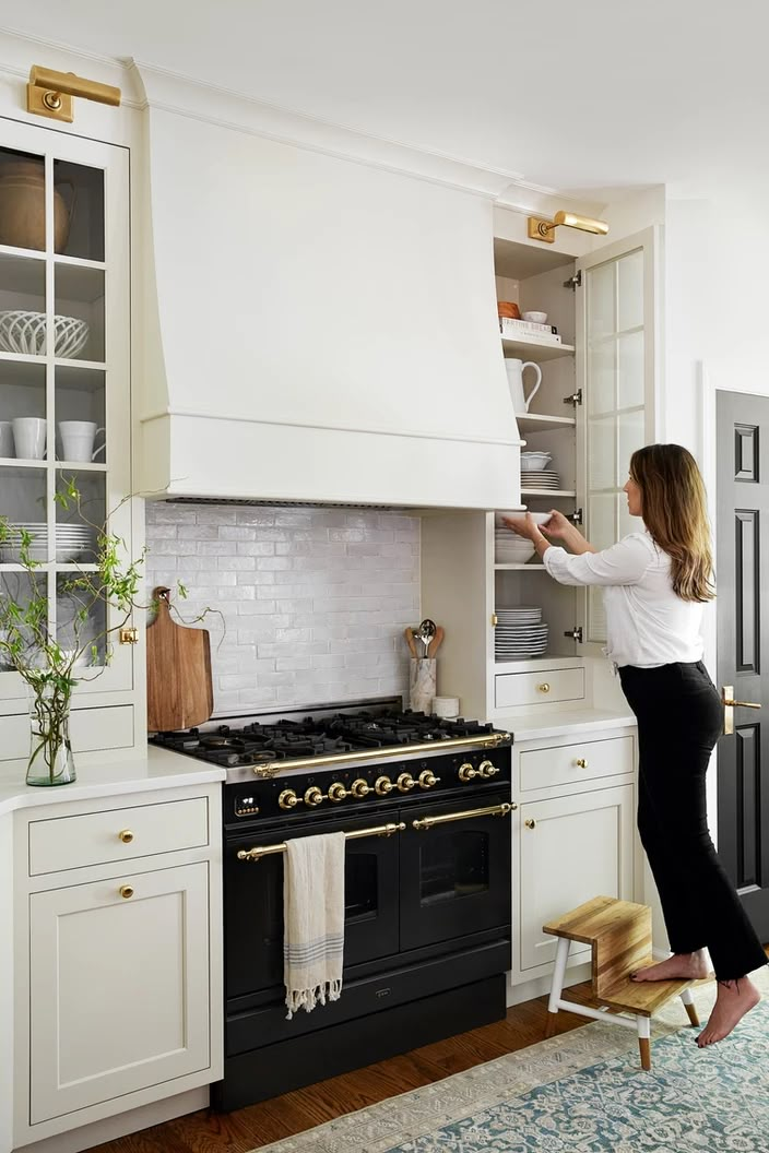 a woman standing in front of an oven and holding the hood up to open it