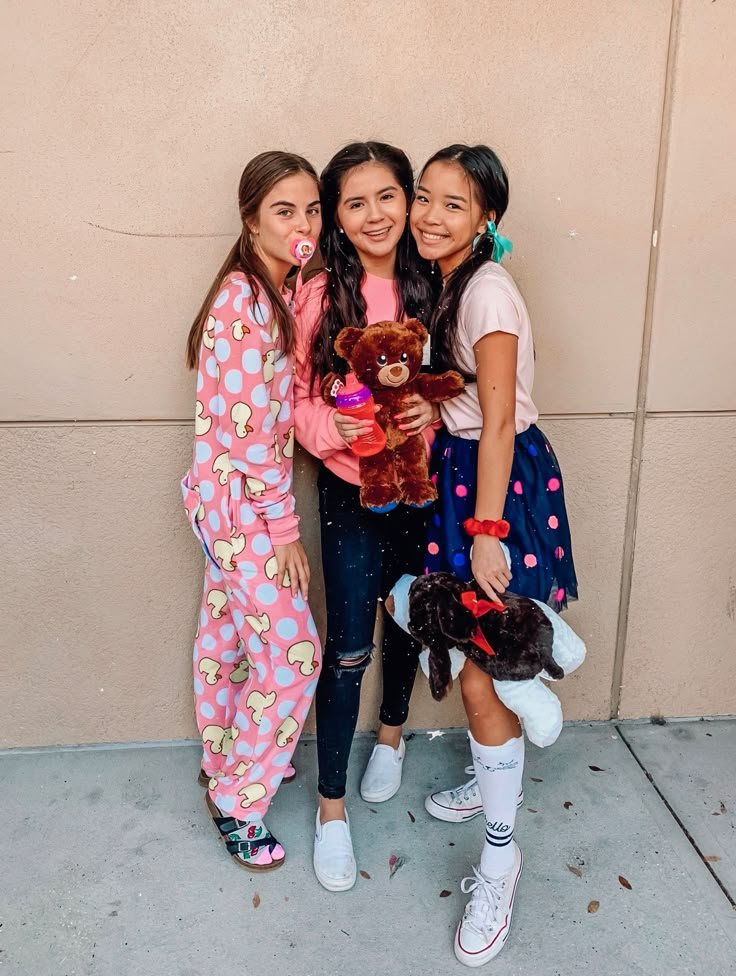 three girls standing next to each other with stuffed animals in their hands and one holding a teddy bear