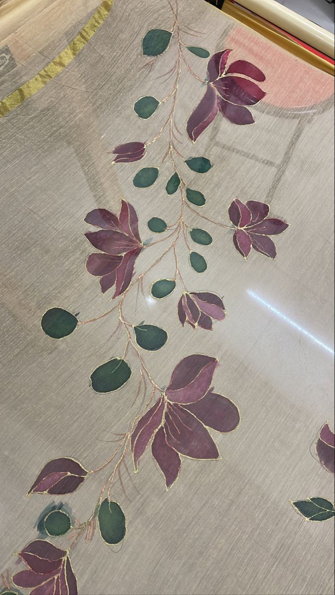 an embroidered cloth with leaves on it is being displayed in front of a tablecloth